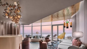 A modern interior with a large window overlooking the sea, a round coffee table, and a variety of seating options.