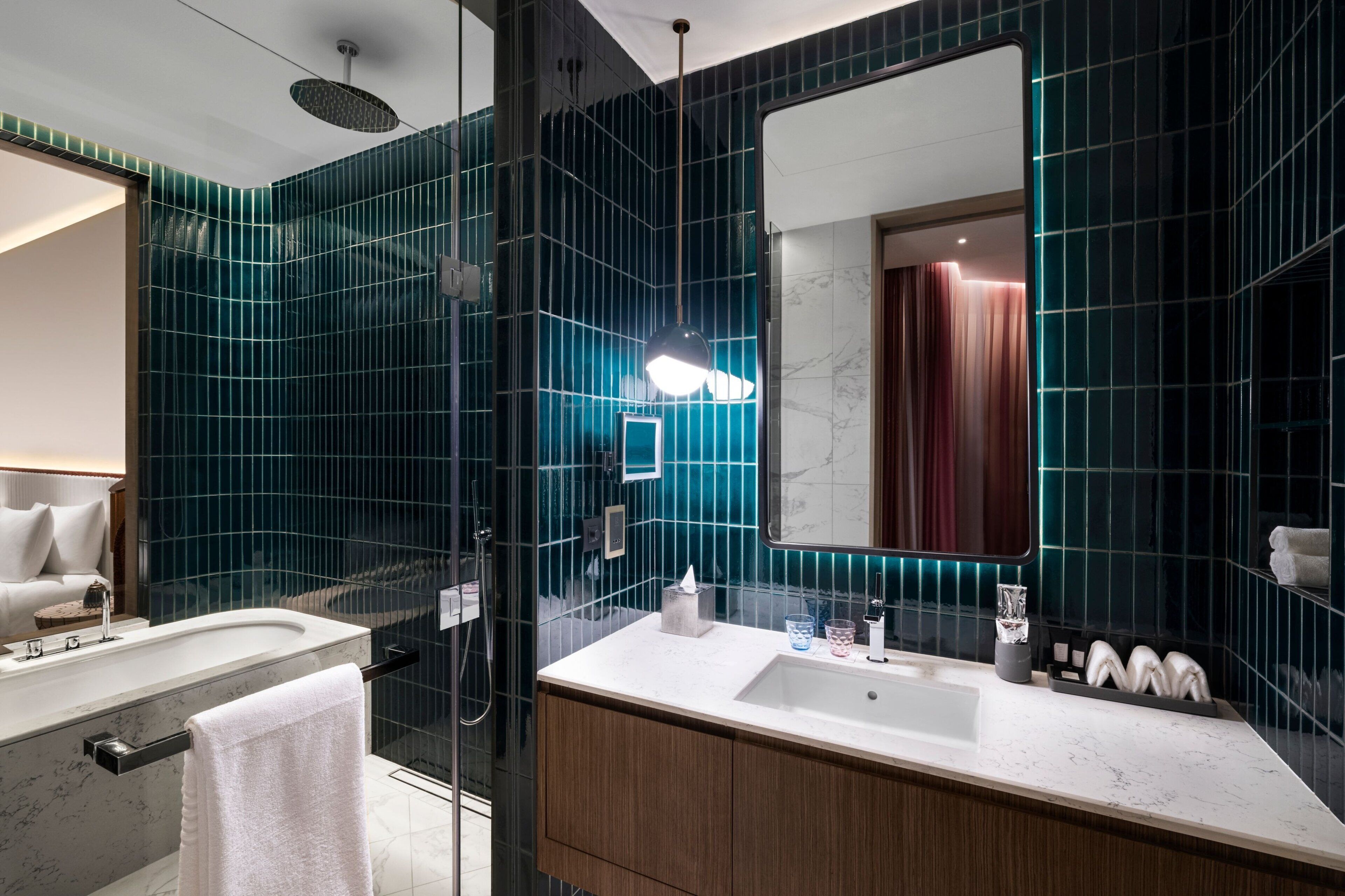 A modern bathroom with a large mirror, a bathtub, and a vanity with a sink.
