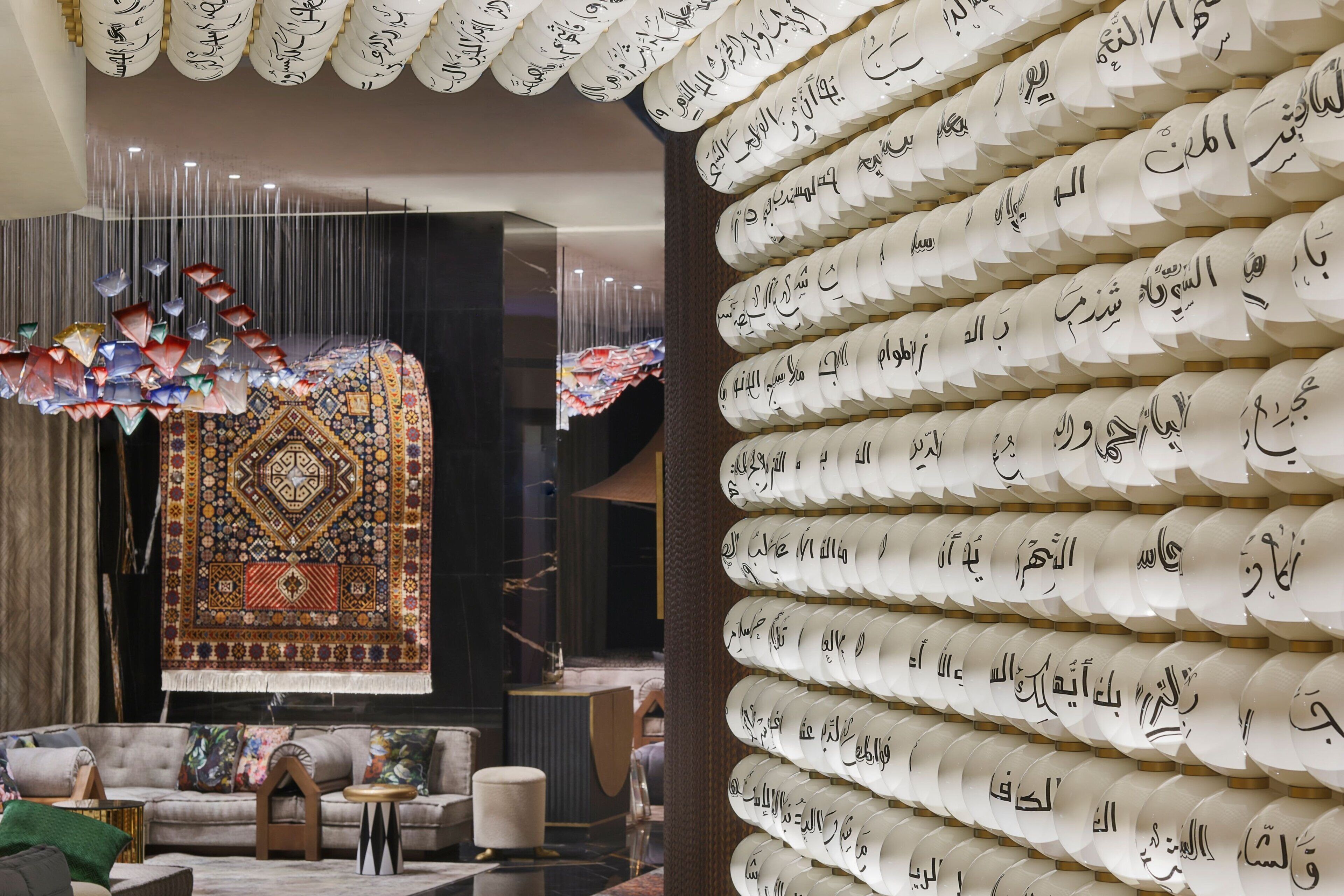 Un intérieur moderne agrémenté d’un tapis à motifs, d’un canapé et d’un mur orné de calligraphies.