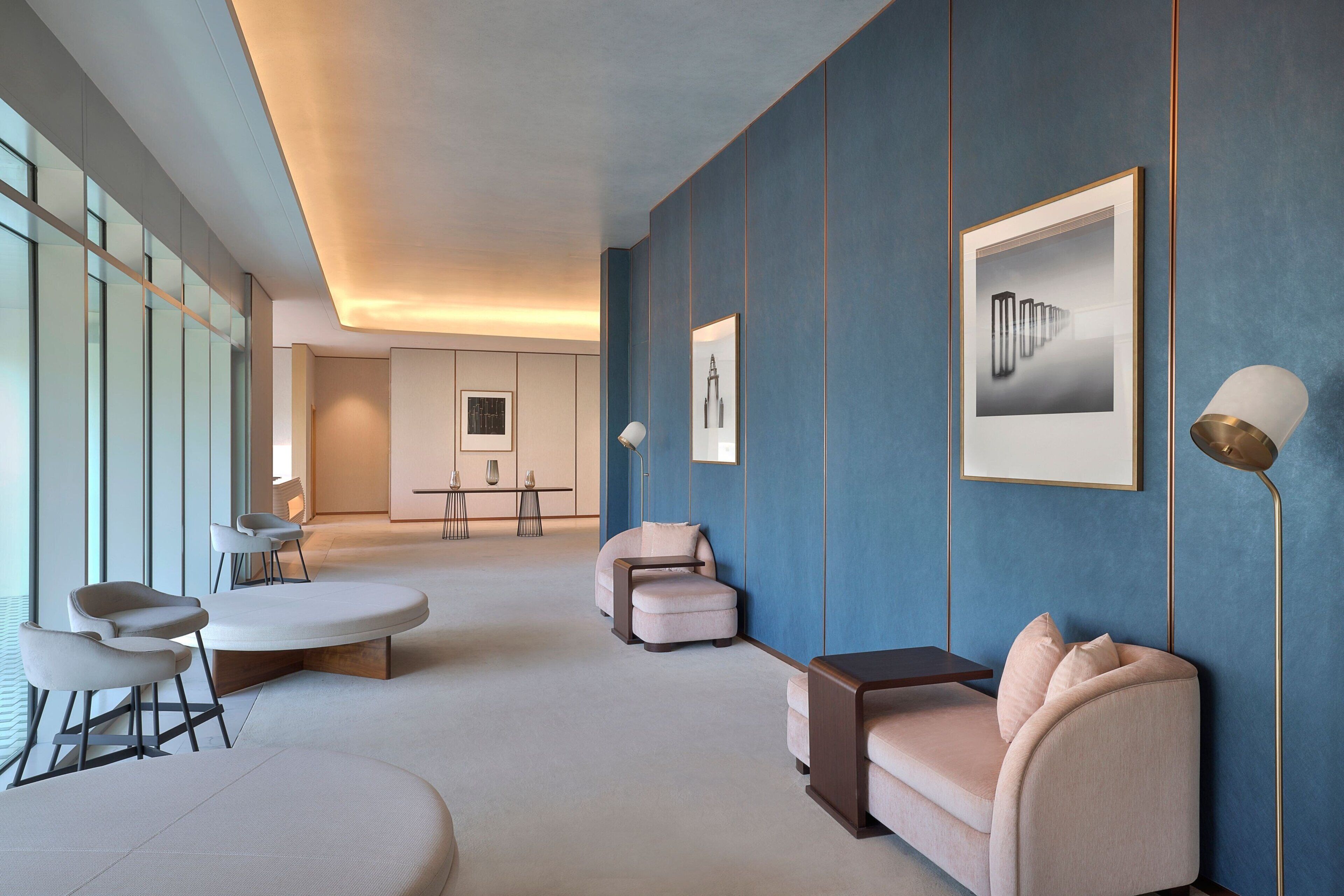 A modern interior with a sofa, armchairs, and a coffee table. There are framed pictures on the wall and a lamp on a side table.