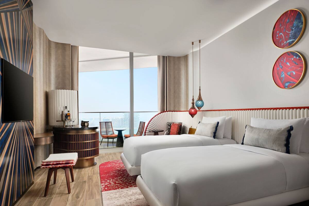 Une chambre d’hôtel moderne avec deux lits, une télévision, un bureau et une vue sur la ville.