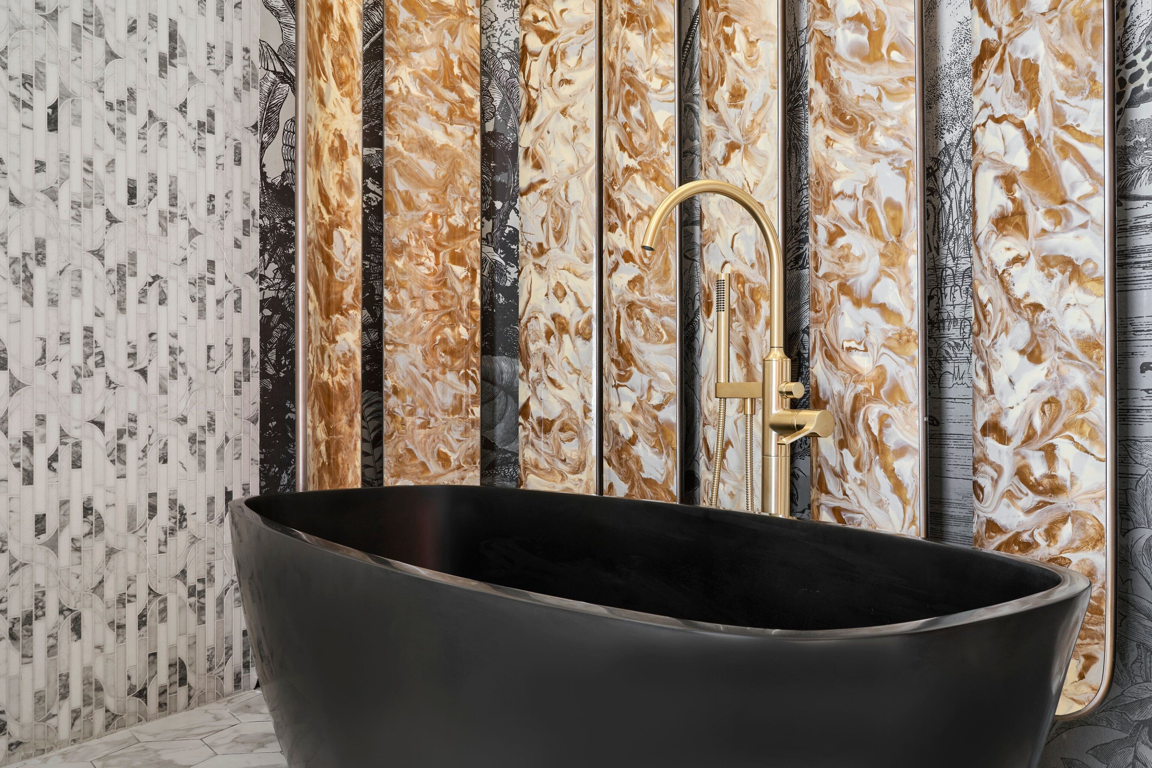 A freestanding bathtub with a gold faucet in a bathroom with patterned wallpaper.