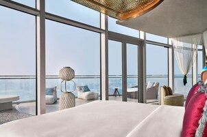 Habitación de hotel en un rascacielos con una cama grande, vistas a la ciudad y un balcón con asientos.