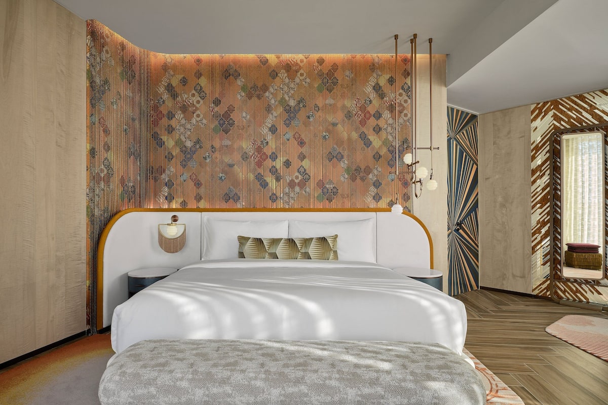Une chambre moderne avec un grand lit, une tête de lit à motifs et un décor mural original.