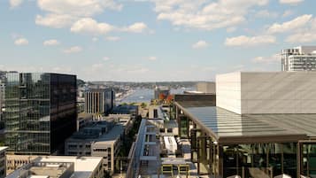 A modern building with a rooftop terrace featuring outdoor seating and a view of a river.