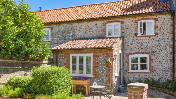 Une maison en pierre avec un toit en tuiles, un petit jardin et un étang.