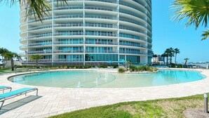 A modern hotel with a curved facade, a swimming pool, and a view of the ocean. - Bella Luna 810-Spectacular Views of Beach & Bay (Orange)