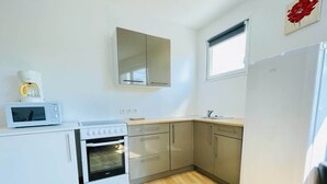 A compact kitchen with a microwave, oven, and refrigerator.