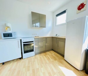 Cocina compacta con microondas, horno y refrigerador.