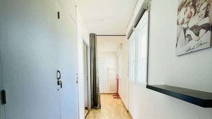 A hallway with wooden flooring, a door on the left, and a wall-mounted artwork on the right.
