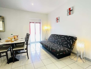 A modern living room with a sofa, dining table, chairs, and a lamp.