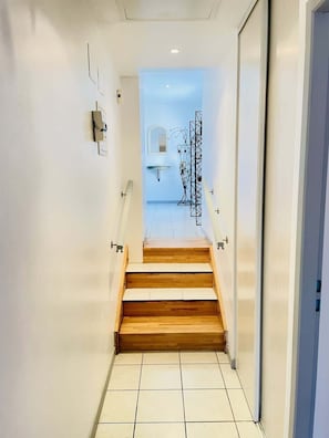 Un escalier menant à une salle de bain équipée d’un lavabo et d’un miroir.