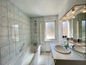 Une salle de bain moderne avec une baignoire, deux lavabos et un grand miroir.