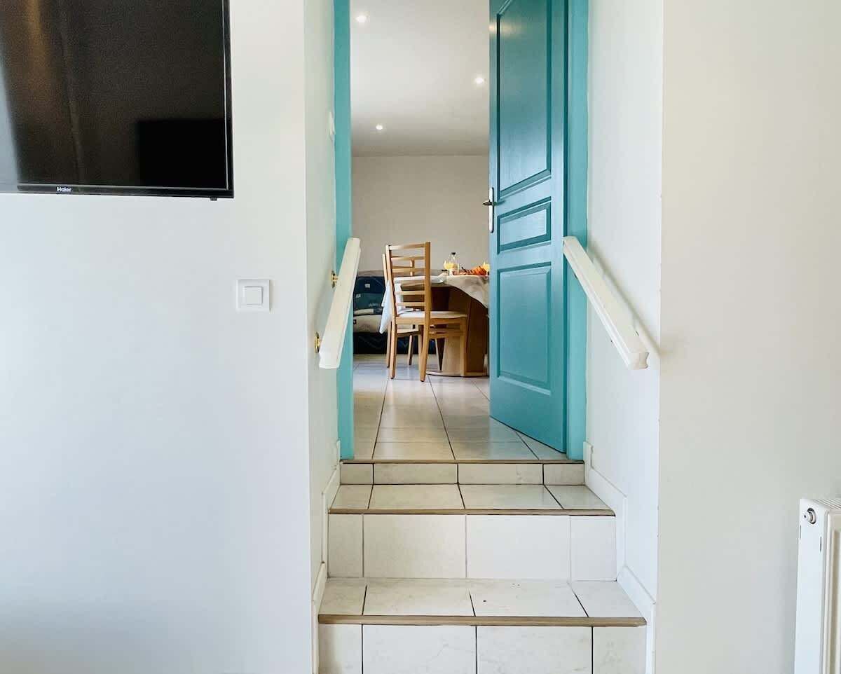 Un escalier menant à une salle à manger équipée d’une table et de chaises.