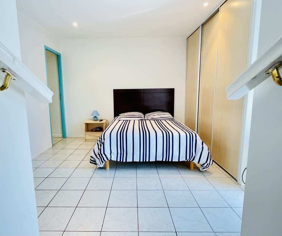Une chambre à coucher avec un lit, une table de chevet, une lampe et une armoire.