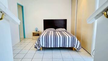 Une chambre à coucher avec un lit, une table de chevet, une lampe et une armoire.