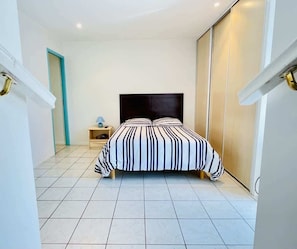 Une chambre à coucher avec un lit, une table de chevet, une lampe et une armoire.