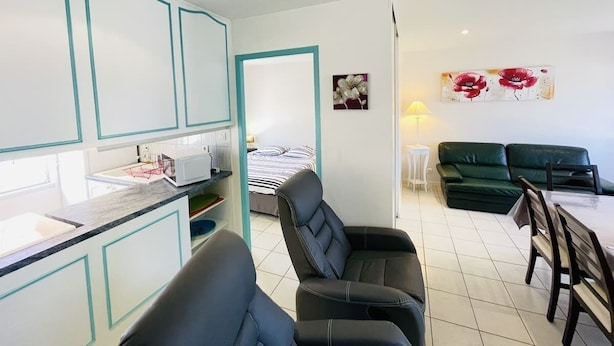 Un espacio habitable compacto con kitchenette, zona de comedor y área de descanso con sofá y sillones.