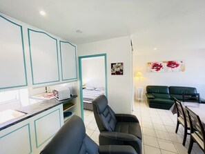 A compact living space with a kitchenette, a dining area, and a seating area with a sofa and chairs.