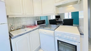 Una cocina con gabinetes blancos, microondas, lavavajillas y estufa.