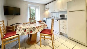 Una cocina con armarios blancos, microondas, refrigerador y una mesa de comedor con sillas.