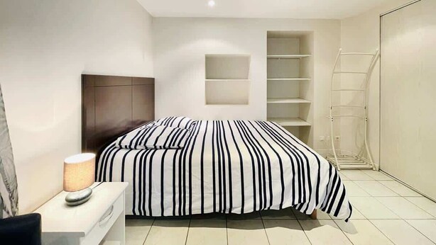 Un dormitorio moderno con cama, lámpara de noche y estanterías empotradas.