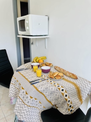 A dining table with breakfast items, a microwave, and a chair.