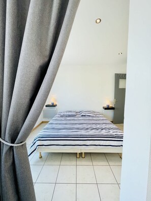 A bedroom with a bed, curtains, bedside tables, and a door.