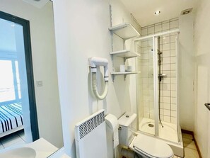A modern bathroom with a toilet, shower, and a visible window.