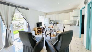 A modern kitchen with white cabinets, a dining table with chairs, and a TV. - Pasteur (Bains-les-Bains)