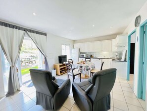 A modern kitchen with white cabinets, a dining table with chairs, and a TV.