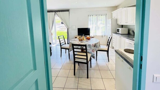 A dining area with a round table, chairs, and a television. - Pasteur (Bains-les-Bains)