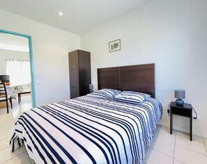 A bedroom with a large bed, a bedside table, a wardrobe, and a chair.