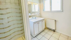 A bathroom with a shower, a sink, a mirror, and a window. - Athos (Bains-les-Bains)