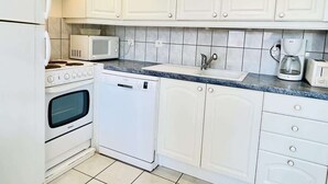 A kitchen with white cabinets, a microwave, a stove, a dishwasher, and a coffee maker. - Athos (Bains-les-Bains)