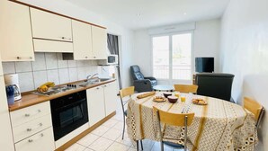 A compact kitchen with a dining table, chairs, and a TV.