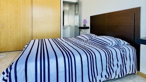 A bedroom with a bed, wooden wardrobe, and a bathroom visible through an open door. - Jacques Prévert (Bains-les-Bains)