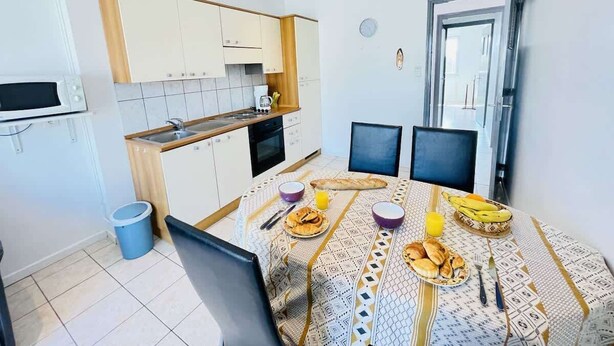 A compact kitchen with a dining area, a microwave, and a sink. - Jacques Prévert (Bains-les-Bains)