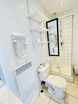 A modern bathroom with a toilet, bidet, shower, and a mirror.