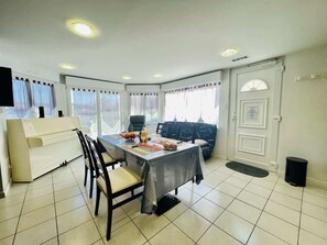 A dining area with a table set for two, a sofa, and a piano.