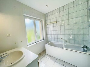 A bathroom with a bathtub, a sink, and a window.