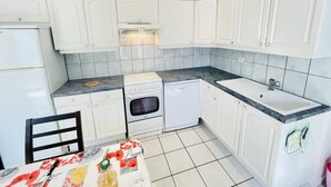 A kitchen with white cabinets, a stove, oven, and a sink. - Louis 11 (Bains-les-Bains)