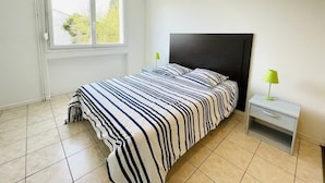 Une chambre à coucher avec un lit, une table de chevet, une fenêtre et une vue sur la verdure.