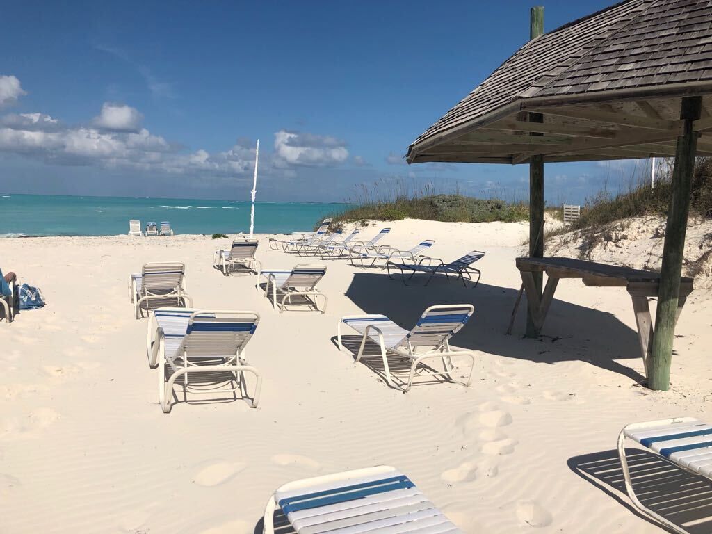 Una spiaggia con lettini e una struttura in legno, probabilmente una capanna balneare, sotto un cielo sereno.