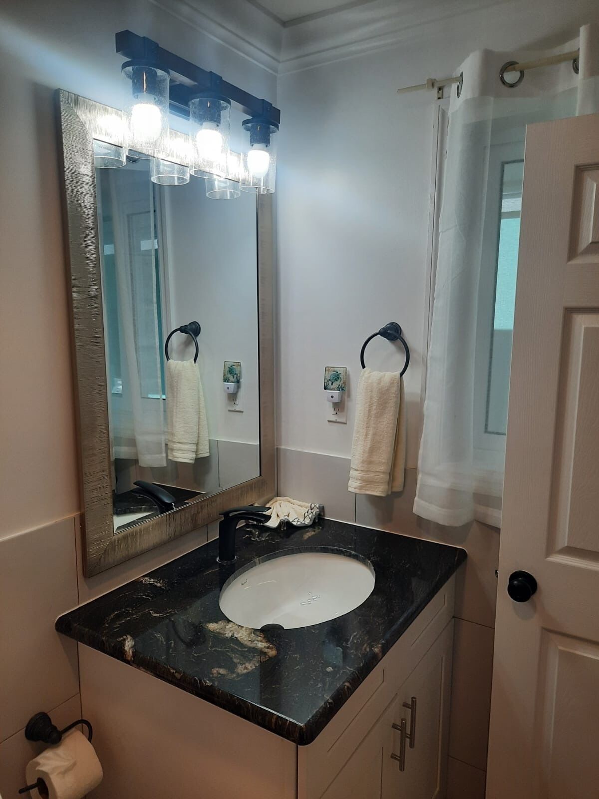 A bathroom with a large mirror, a sink, and a towel rack.