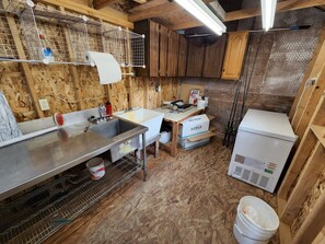 A compact kitchen with a sink, countertop, and wooden cabinets. - Kenai River Getaway (Soldotna)