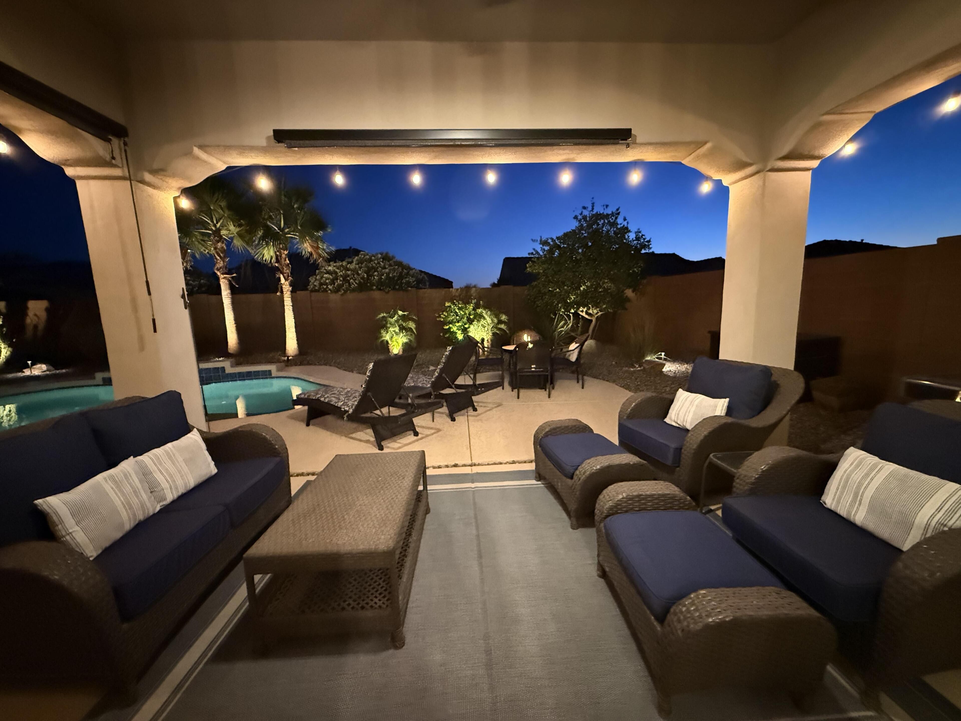 An outdoor patio area with lounge chairs, a pool, and a view of the night sky.