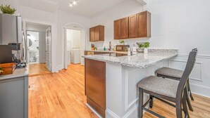 Cocina con una isla central, armarios de madera y un refrigerador de acero inoxidable.