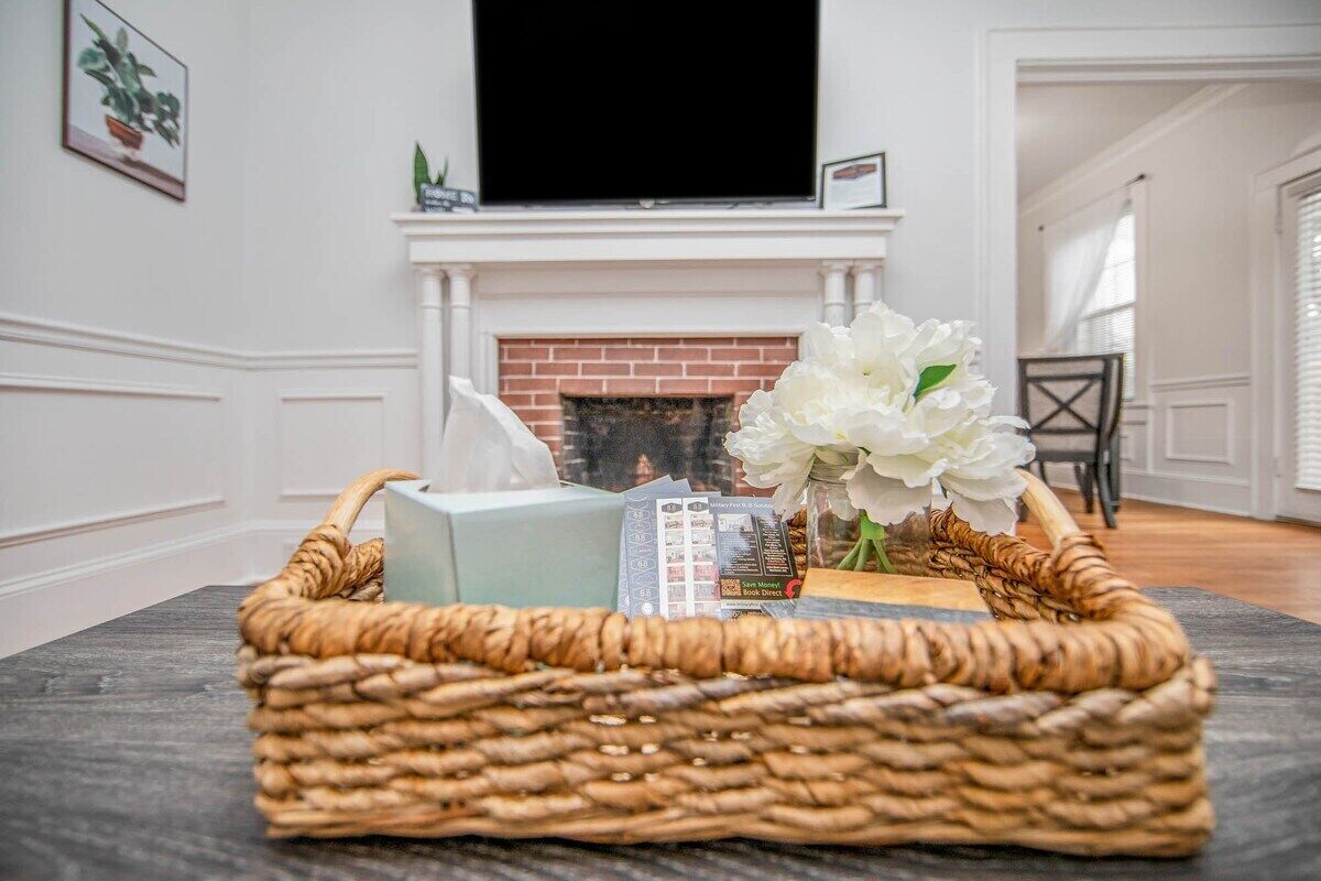 A living room with a fireplace, a television mounted above it, and a wicker basket on the floor.