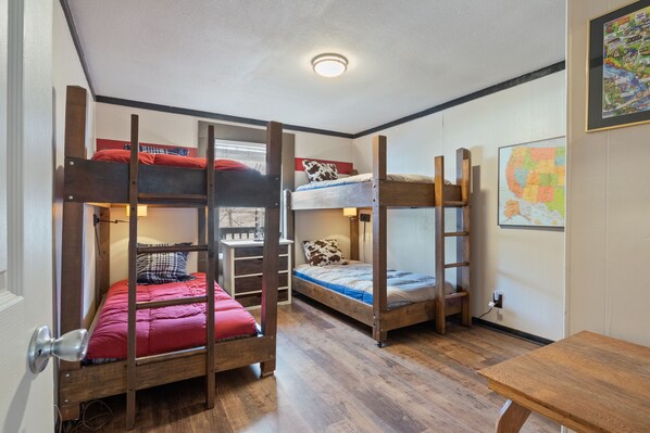 A room with bunk beds, a wooden desk, and a map on the wall.